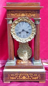 Pendola da tavolo in legno di palissandro con intarsi in acero.4 colonne filettate. Decorazioni in bronzo dorato. Quadrante in argento lavorato